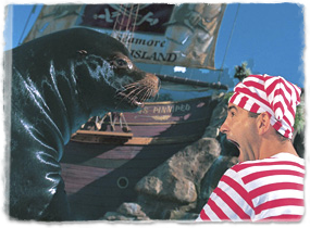A costumed trainer makes an exaggerated gasp gesture face-to-face with a sea lion during a show.