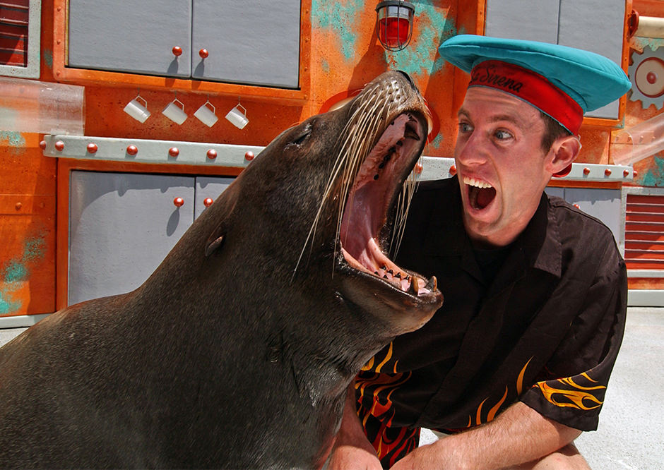 a trainer and sea lion making comedic exaggerated mouth movements