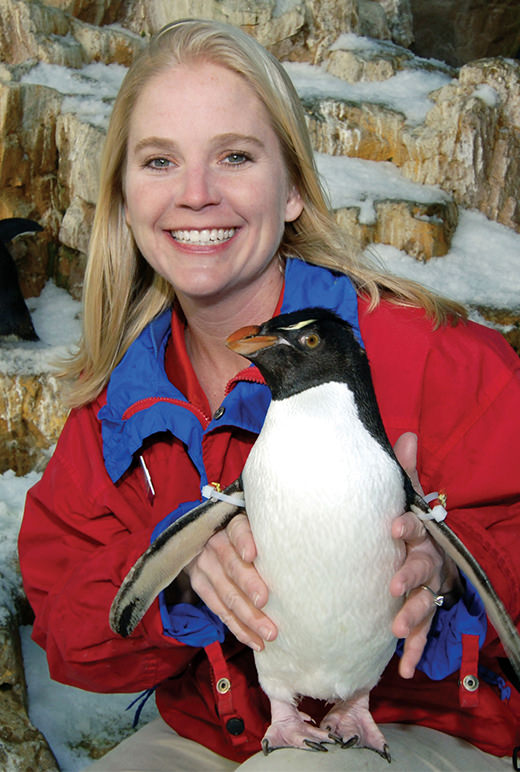An aviculturist poses with a penguin